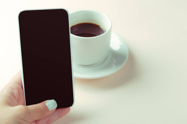smartphone in female hand and coffee on table - Foto, Imagen