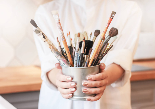Different brushes in metal bucket with artist hands, selective focus - Fotografie, Obrázek