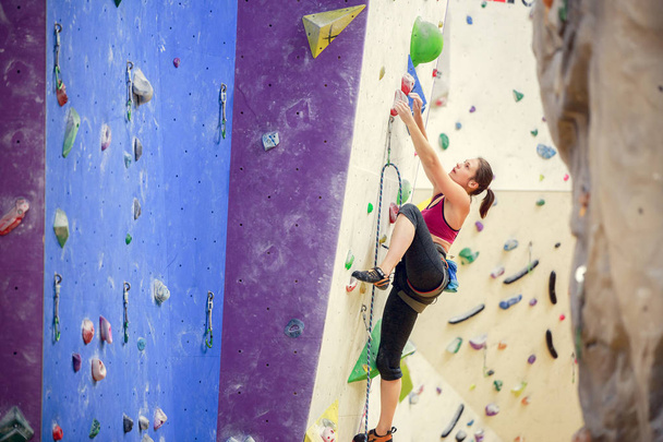 Photo of sportswoman in training on purple wall for rock climbing - Fotoğraf, Görsel