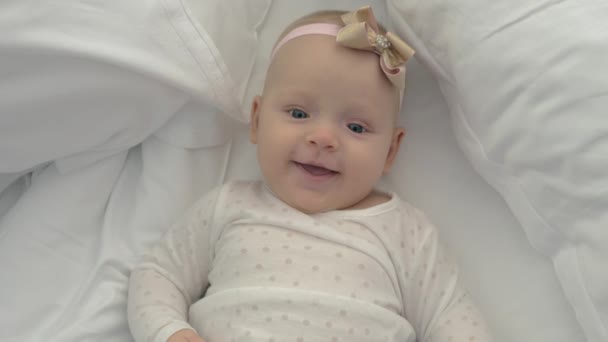 Smiling blue-eyed baby girl with bow - Imágenes, Vídeo