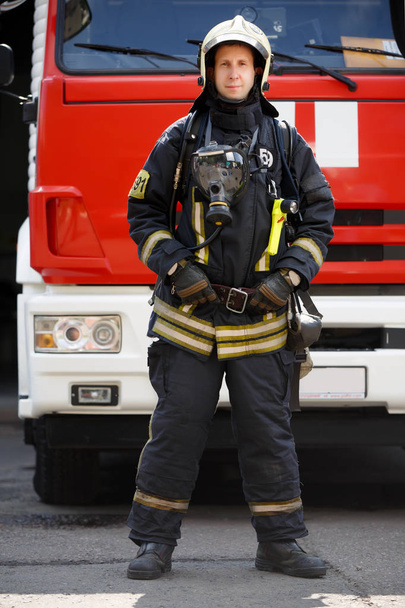 Photo in full growth of fireman on background of fire engine machine at station - Fotografie, Obrázek