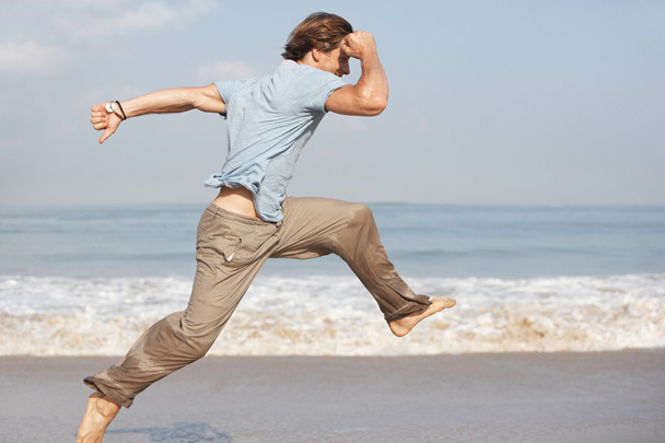 Junger Mann springt im Urlaub ans Meer. - Foto, Bild