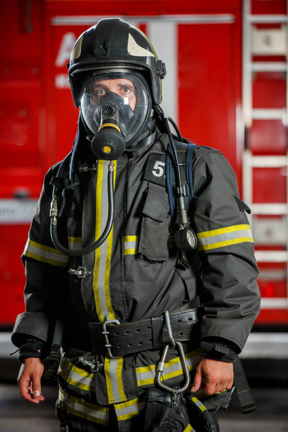 Photo of fireman in gas mask and helmet near fire engine - Foto, Bild