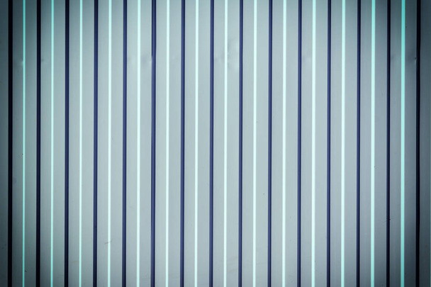 Wall of corrugated metal. Beautiful bluish background with vertical stripes. Photo with a vignette. - Photo, Image