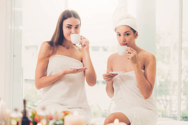 Dos mujeres que beben té o bebidas de hierbas mientras conversan en un spa de lujo. Bienestar, ocio y salud
. - Foto, Imagen