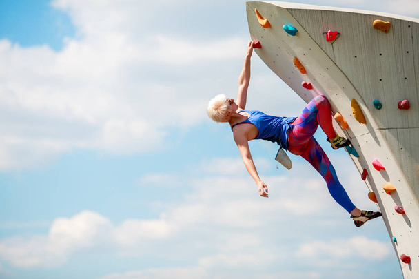 Photo from side of sports girl climbing on rocky summer day - 写真・画像