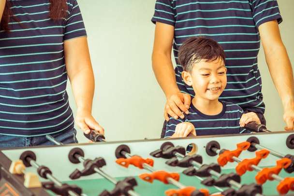 Happy kid playing foosball table soccer with family, father and mother. - Photo, Image