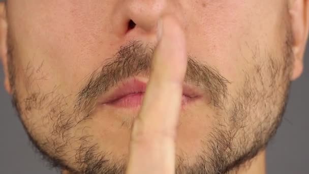 hombre pone su dedo en sus labios, un gesto de silencio o secreto, primer plano
 - Metraje, vídeo