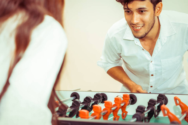 Happy young man playing foosball table soccer with girlfriend. Couple recreation and lifestyle. - Fotoğraf, Görsel