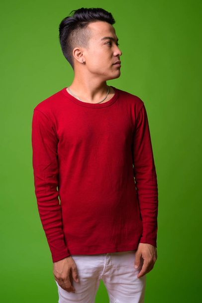 Giovane uomo multietnico indossa maglione rosso sullo sfondo verde
 - Foto, immagini