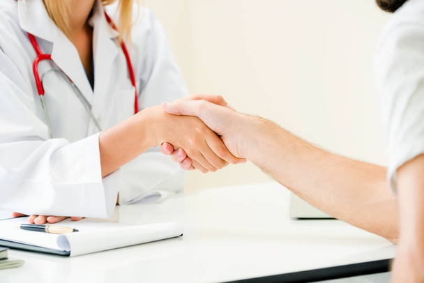 Žena doktor dělá handshake s mužský pacient v nemocnici úřadu. Služby zdravotní péče a lékařských povolání. - Fotografie, Obrázek
