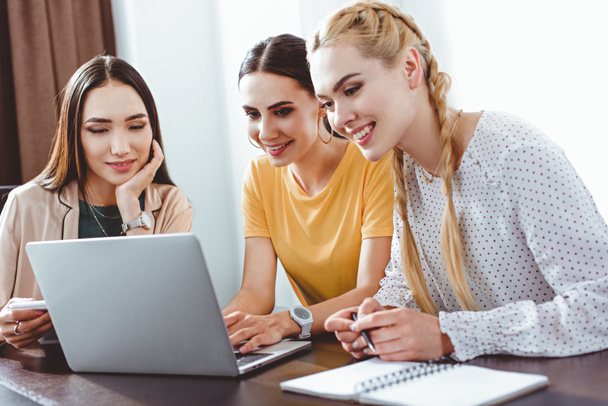 drie multicultureel zakenvrouwen met behulp van laptop aan tafel in de moderne kantoor  - Foto, afbeelding