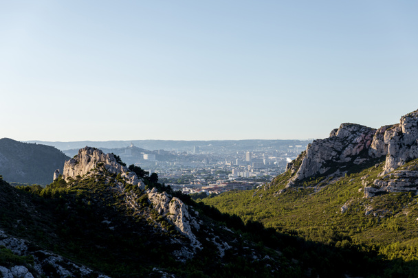 gyönyörű sziklás-hegység, a zöld növényzet és a távoli falu Provence, Franciaország - Fotó, kép