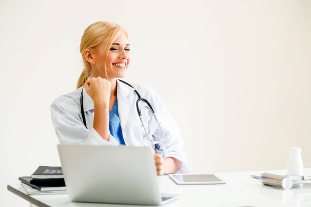 Happy successful woman doctor feels delightful in hospital or healthcare institute while working on medical report at office table. Success concept. - Foto, imagen