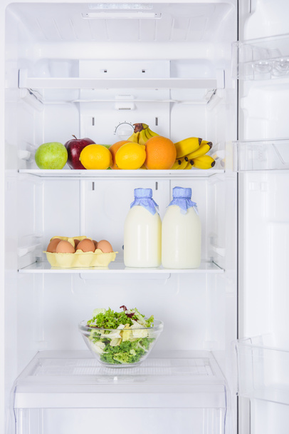 fruits, bottles of milk and salad in fridge - Fotoğraf, Görsel