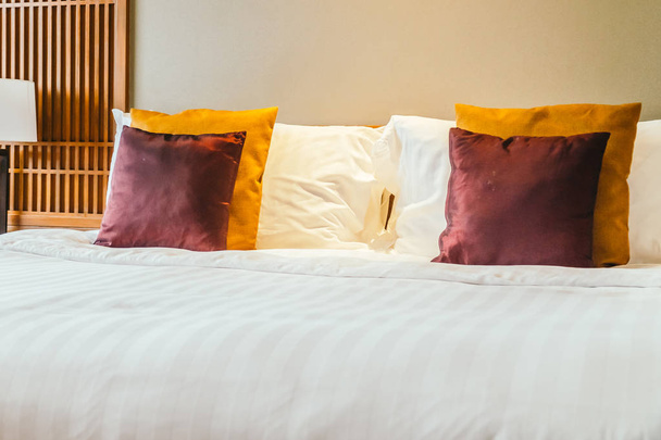 Comfortabel kussen op het bed met licht lamp meubels decoratie interieur van hotel slaapkamer - Foto, afbeelding