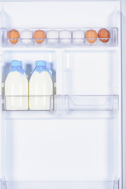 chicken eggs and bottles of milk in fridge - Fotoğraf, Görsel