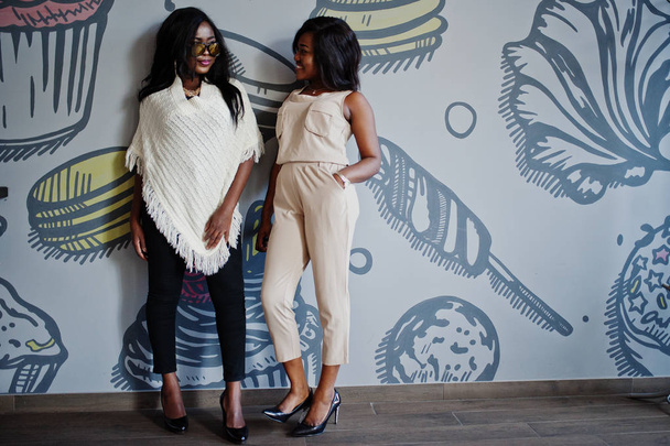  Two stylish african american girls at cafe posed against wall. - Fotó, kép