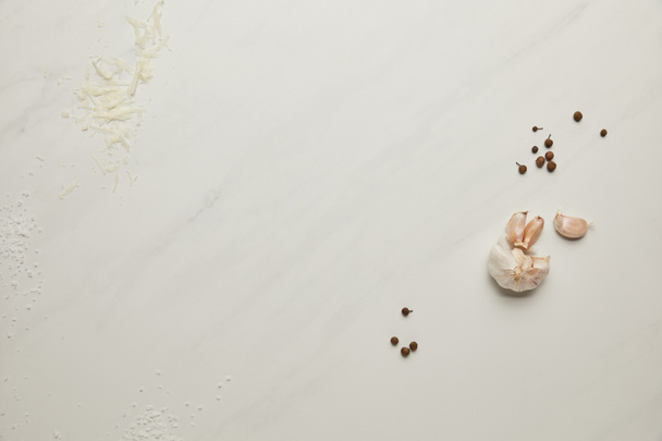 plochý lay uspořádány mouku, strouhaný sýr, česnek a pepř černý na bílém stole - Fotografie, Obrázek