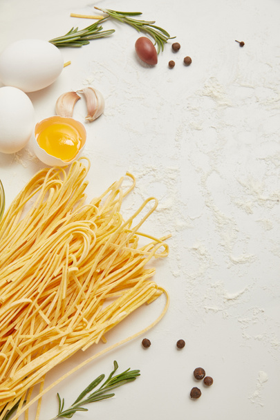 Nahaufnahme von ungekochten Makkaroni, rohen Hühnereiern und Mehl zum Kochen von Pasta auf weißer Oberfläche - Foto, Bild