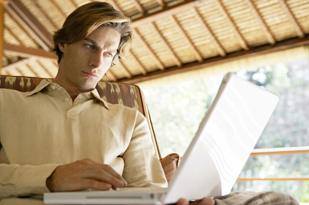 Young professional man in an exotic location using a laptop computer. - Photo, Image
