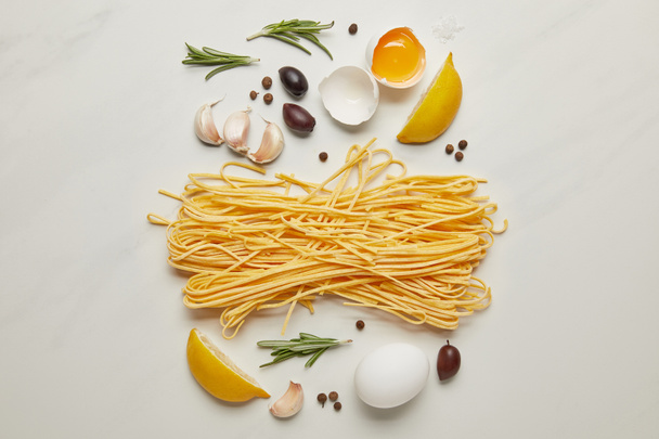 lat plana con ingredientes de pasta italiana surtidos dispuestos en la superficie de mármol blanco
 - Foto, imagen