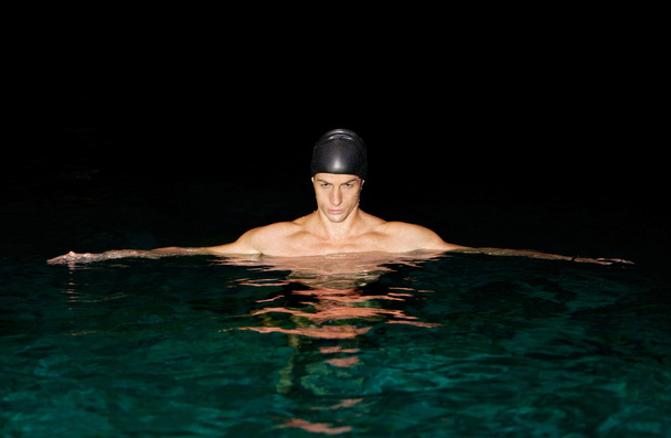 Uomo che si prepara per l'allenamento di nuoto in piscina di notte
. - Foto, immagini