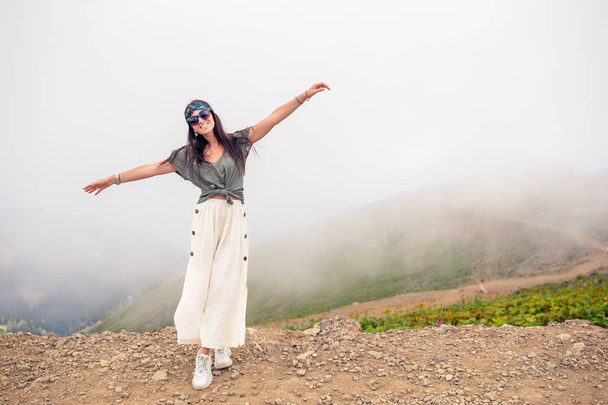 Belle jeune femme heureuse dans les montagnes dans le fond de brouillard - Photo, image