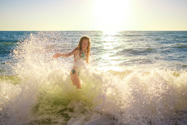 молодая стройная красивая женщина на пляже заката, игривая, танцующая, бегущая, феминистский наряд, инди-стиль, летний отдых, солнечная, веселая, позитивное настроение, романтичная, плещущая воду, силуэт, счастливая, тонированная
 - Фото, изображение