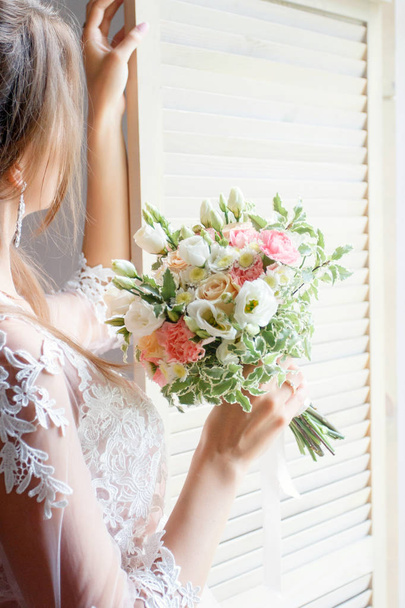 νύφη στο παράθυρο, με μια ανθοδέσμη σε ένα στούντιο φωτογραφίας - Φωτογραφία, εικόνα