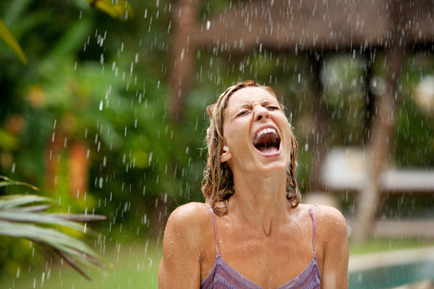 aantrekkelijke vrouw onder tropische regen in een exotische tuin - Foto, afbeelding