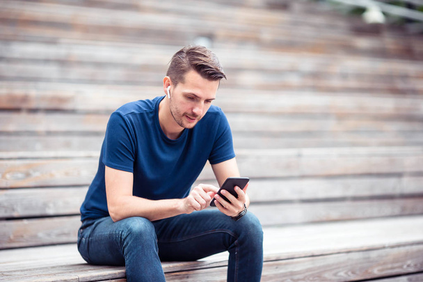 Homem está lendo mensagem de texto no celular enquanto caminha no parque
 - Foto, Imagem