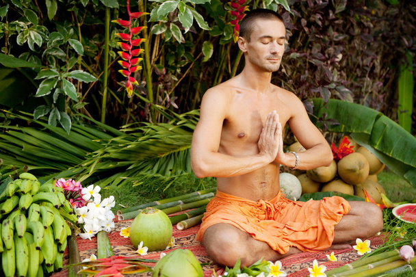 Молодой человек в положении йоги в экзотическом саду
. - Фото, изображение