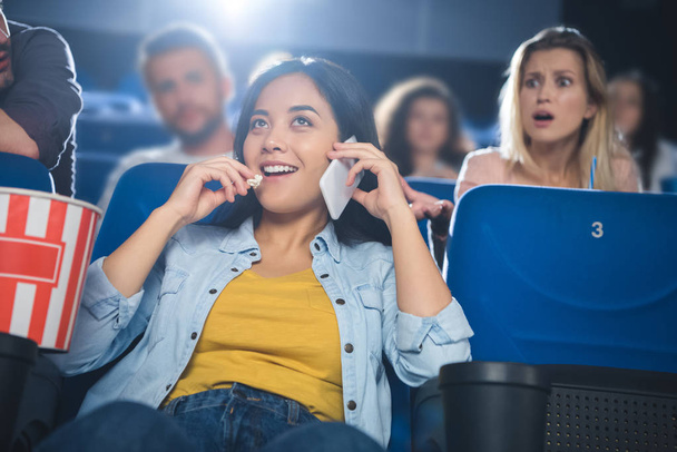 Asian kobieta rozmawia na smartfonie podczas oglądania filmu w kinie - Zdjęcie, obraz