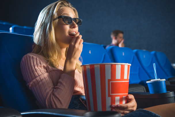 side view of young woman in 3d glasses with popcorn watching film alone in cinema - Foto, Bild
