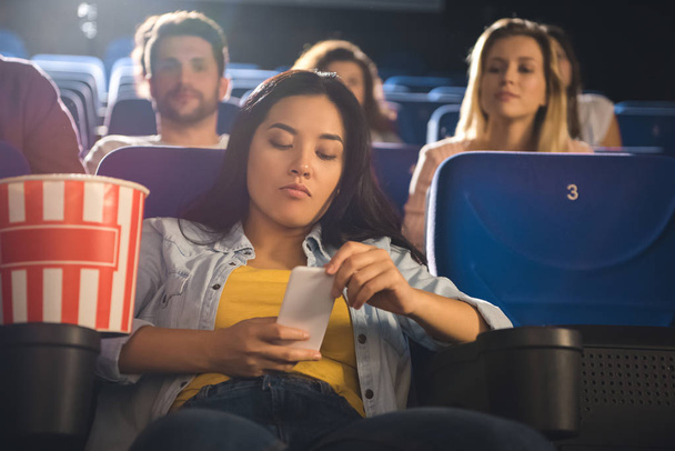 Asyalı kadın film sinemada izlerken Smartphone kullanarak - Fotoğraf, Görsel