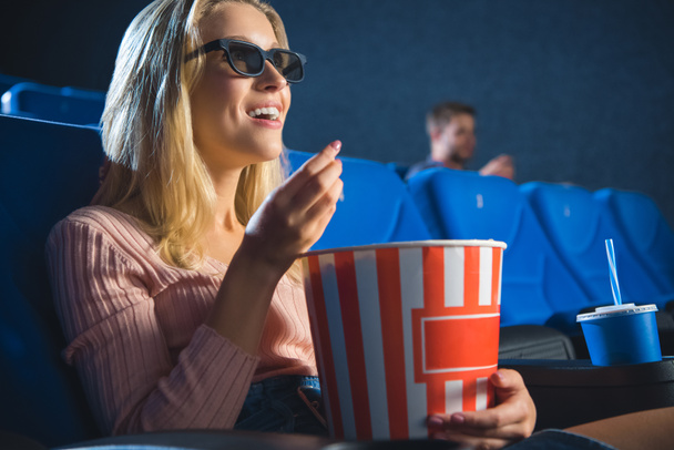 Lächelnde Frau in 3D-Gläsern mit Popcorn, die sich Film allein im Kino ansieht - Foto, Bild