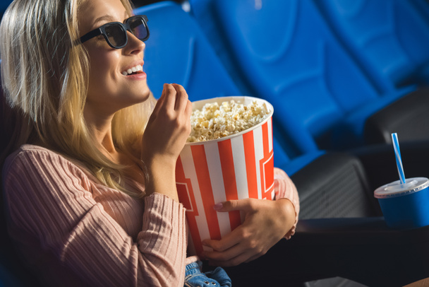 side view of smiling woman in 3d glasses with popcorn watching film alone in cinema - Fotografie, Obrázek