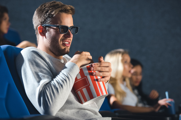 side view of disgusted man in 3d glasses with popcorn watching film in cinema - Φωτογραφία, εικόνα