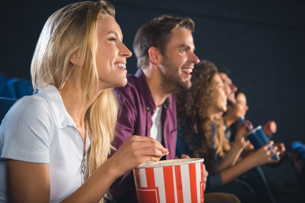 cheerful friends with popcorn watching film together in movie theater - Фото, зображення