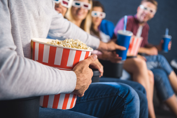 partial view of multiethnic friends with popcorn watching film together in movie theater - Photo, Image
