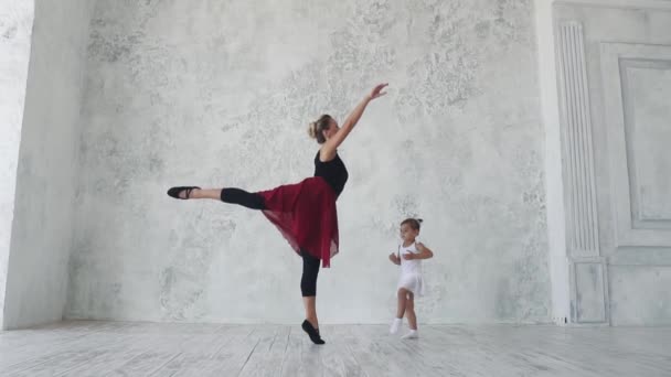 little ballerina in a tutu in ballet class. ballet teacher and a little girl student dancing together. slow motion - Footage, Video