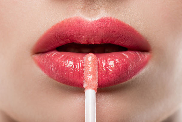 close up of young woman applying lip gloss  - Фото, изображение