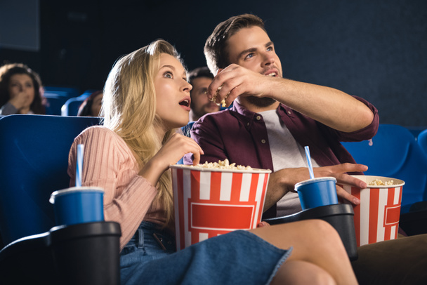 emotional couple with popcorn watching film together in cinema - Valokuva, kuva