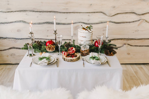 珍しいケーキ、キャンドル、背の高いメガネとモミの枝、木製の背景 - カップルのための新年ディナーの組成 - 写真・画像