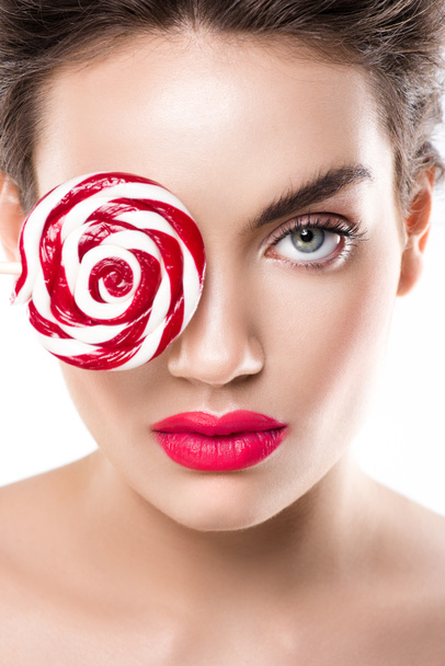 beautiful fashionable girl holding red lollipop in front of eye, isolated on white - Fotó, kép