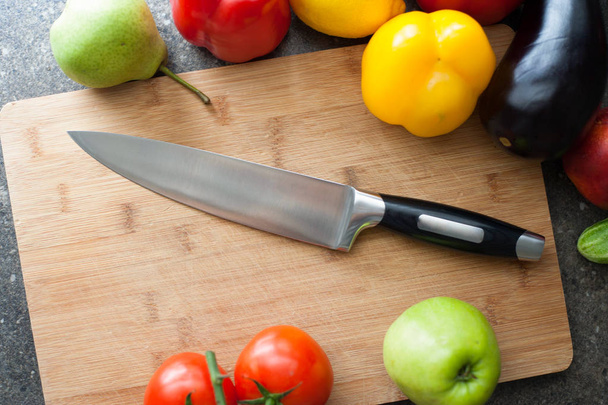Still life of vegetables and kitchen-knife on cutting board - Foto, afbeelding