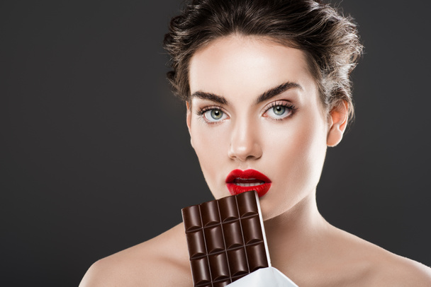 stylish beautiful woman holding chocolate bar, isolated on grey - 写真・画像