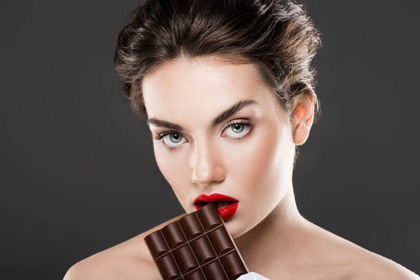 attrayant femme à la mode tenant barre de chocolat, isolé sur gris
 - Photo, image