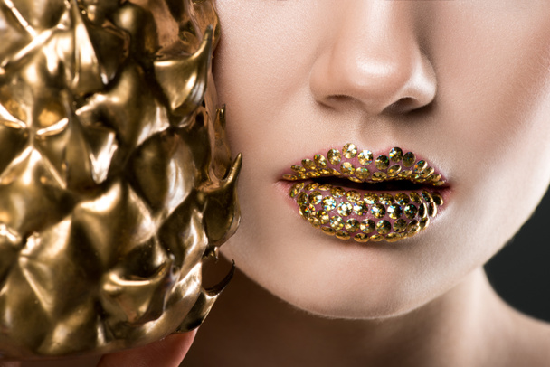 cropped view of woman with gild lips holding golden pineapple  - Fotoğraf, Görsel